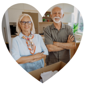 A senior couple stands over moving boxes.